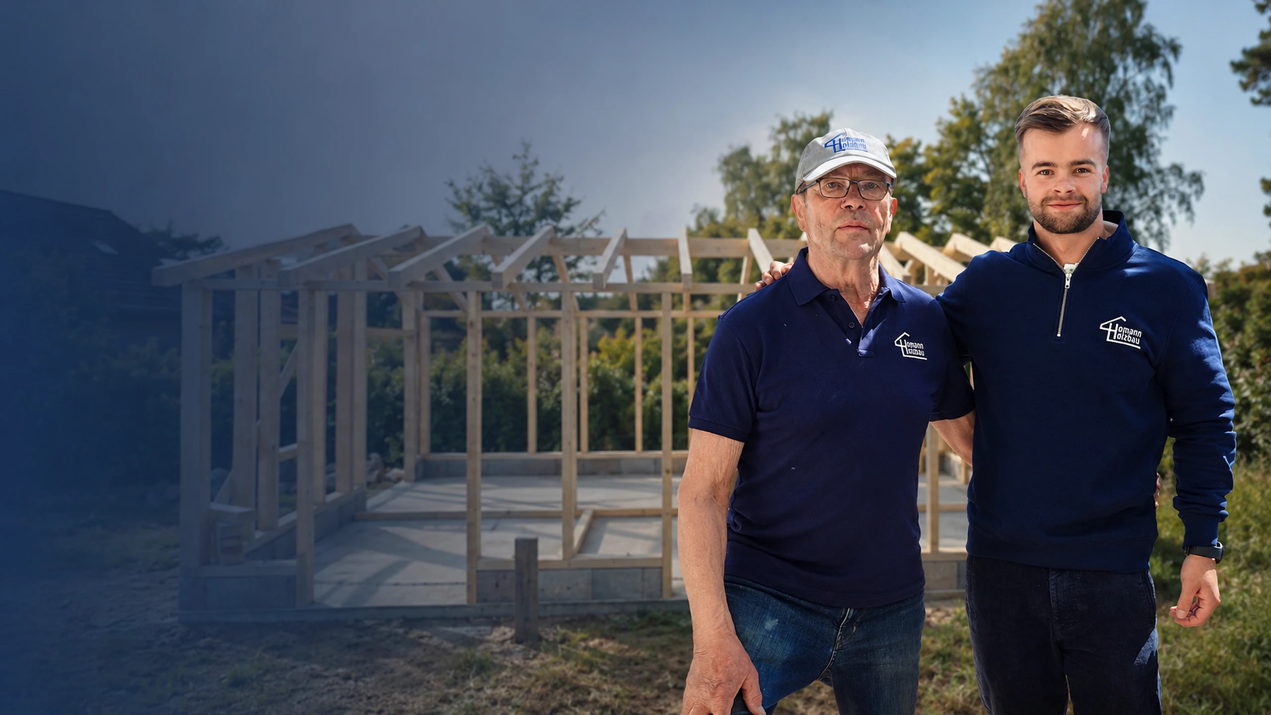 Leon Homann mit seinem Opa vor einem Holzrahmenbau im Rohbau, beide im Homann Holzbau Outfit